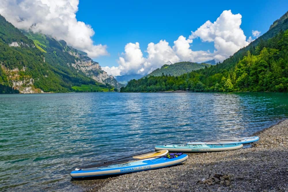 Sup-Boards am Ufer eines Sees mit den Glarner Alpen im Hintergrund.