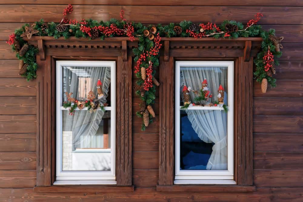 Zwei wunderschön mit Stechpalmen und Beeren dekorierte Holzfenster in Saas-Fee.